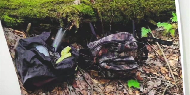 Camo bags and other supplies hidden under a mossy log in the woods of Pennsylvania