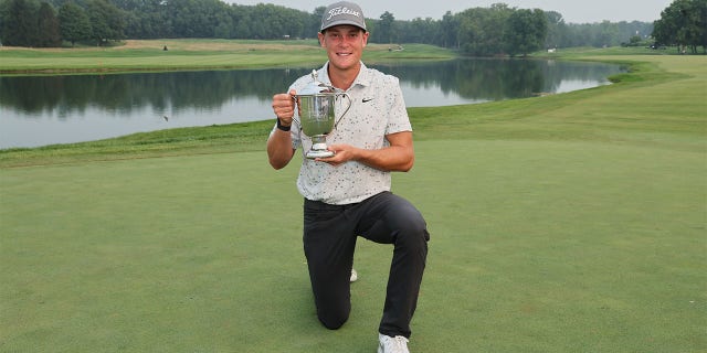 Vincent Norrman kneels with the trophy