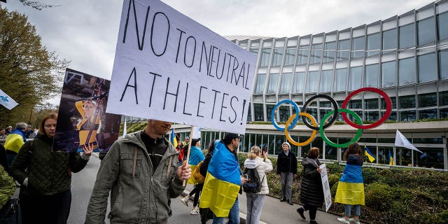Ukrainian protesters walk past the IOC headquarters