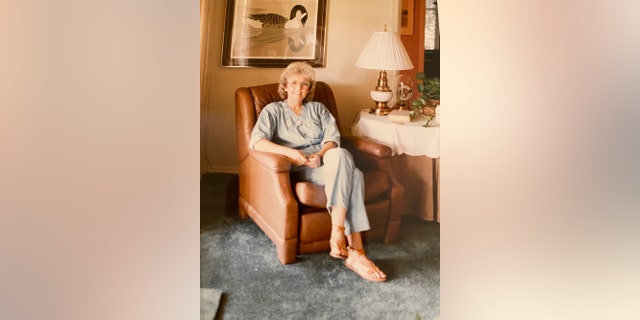 Loretta Bowersock wearing a light blue shirt and matching pants sitting on a tanned couch