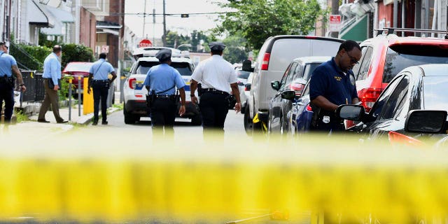 Police officers work at the scene the day after a shooting in Philadelphia