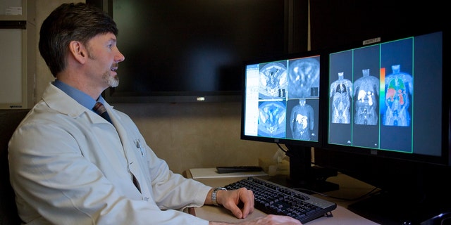 A radiologist compares a CT scan to a choline C-11 PET scan of a patient with recurrent prostate cancer