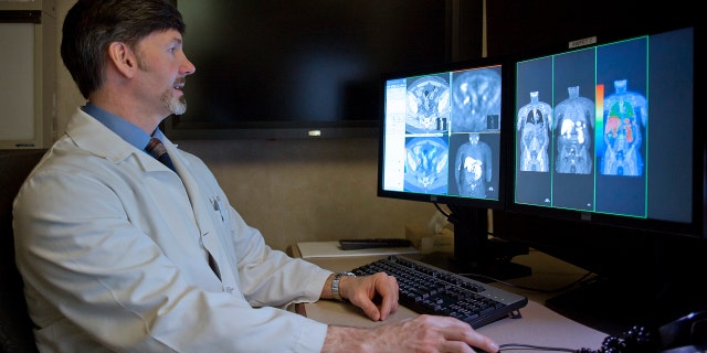 A radiologist compares a CT scan to a choline C-11 PET scan of a patient with recurrent prostate cancer