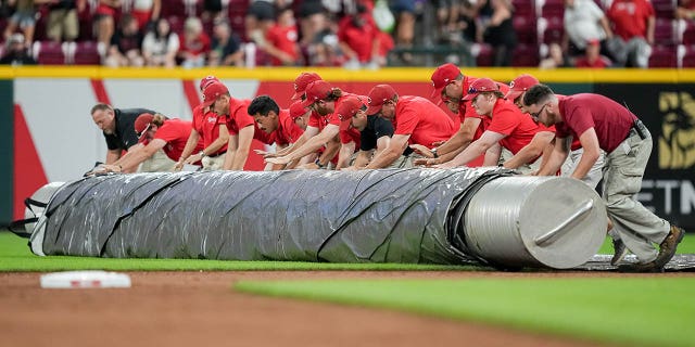 The grounds crew roll out the tarp