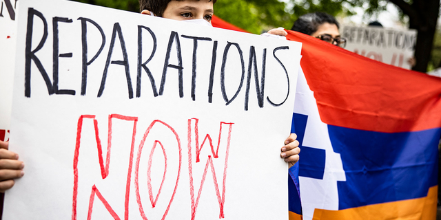 Boy holds reparations sign