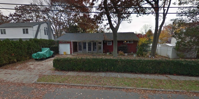 Red house with wrapped up car in driveway and leaves falling