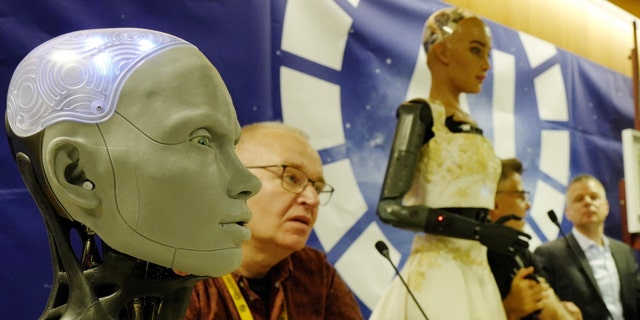 Human shaped robot Ameca (L) beside Will Jackson