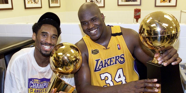 Kobe Bryant and Shaquille O'Neal hold up trophies after winning a championship