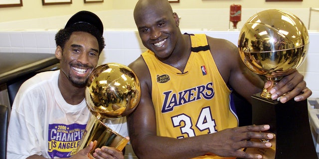 Kobe Bryant and Shaquille O'Neal hold up trophies after winning a championship