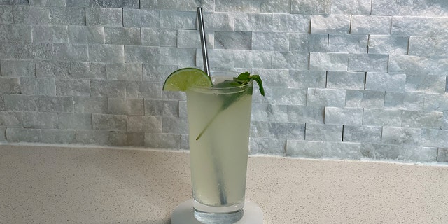 A fully assembled tequila mojito set on a marble coaster in a kitchen.