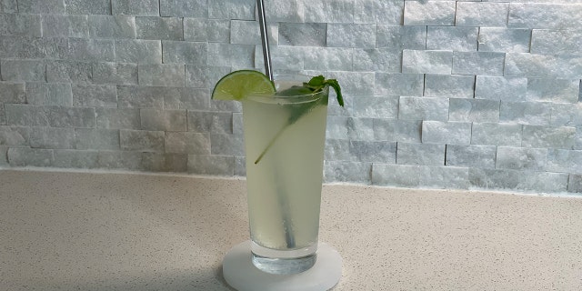 A fully assembled tequila mojito set on a marble coaster in a kitchen.