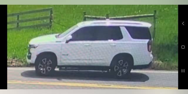 White SUV parked near wooden fence and grassy field