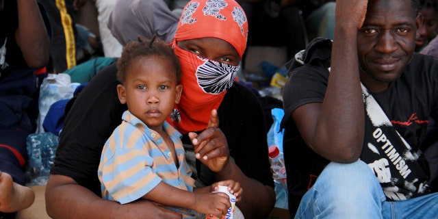 Migrants sit during a gathering