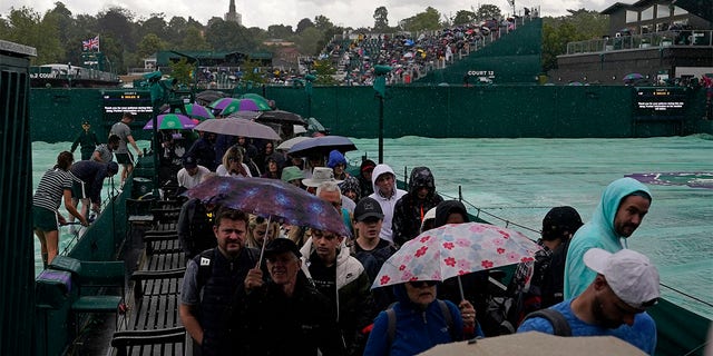 Spectators walk in rain