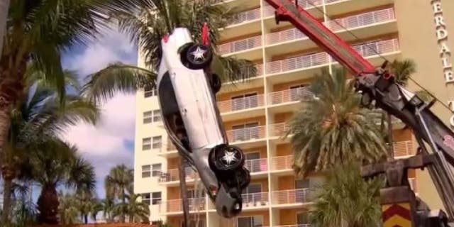 car being pulled from pool by crane