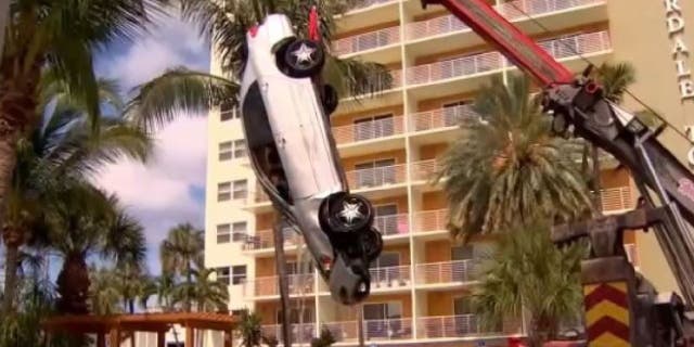 car being pulled from pool by crane