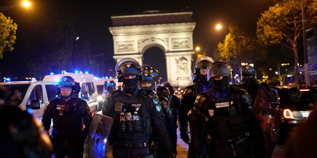 French police in riot gear march near Arc de Triomphe