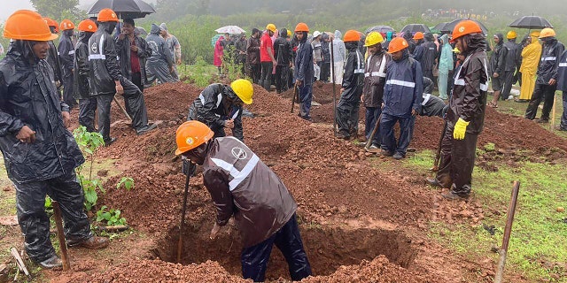 Rescuers dig a grave to bury a victim