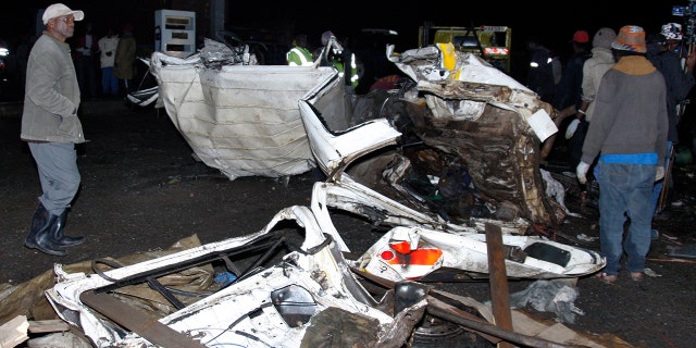 People stand near the wreckage of vehicles in Londiani, Kenya