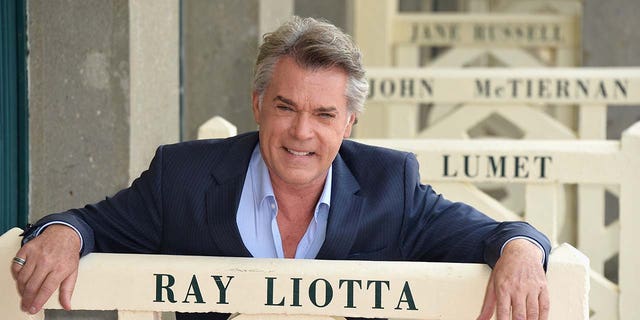 Ray Liotta posing with a sign that has his name on it