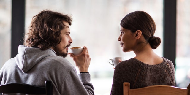 Man and woman talk while drinking coffee.