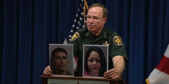Polk County Sheriff Grady Judd holding Joel and Jazmine Rondon's mugshots