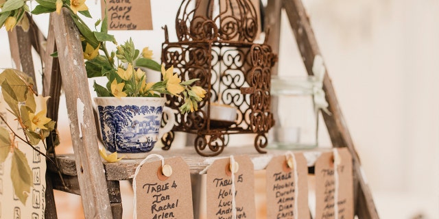 A wooden step ladder at a wedding venue with name place cards for seating arrangements.