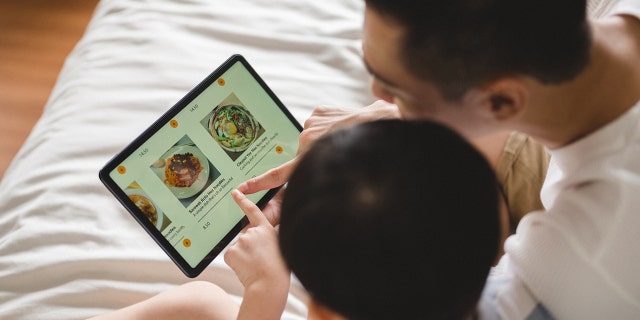 Dad and son look at food menu online.