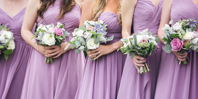 Bridesmaids in purple dresses shown without heads
