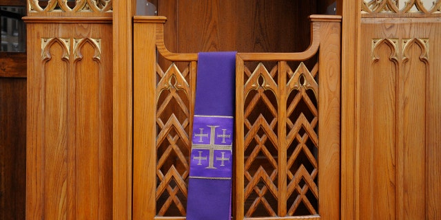 a purple stole with a jerusalem cross hangs over a confessional