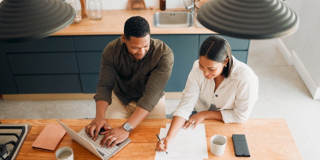 Couple reviews paperwork in kitchen.
