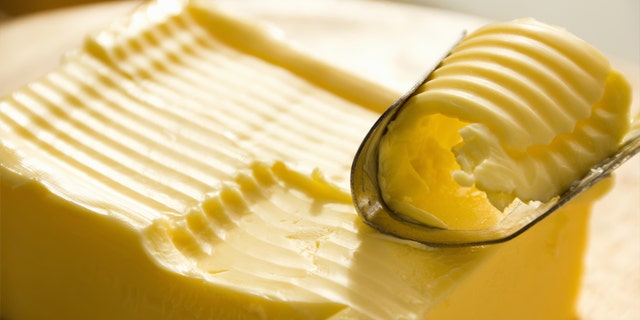 A butter knife with visible holes is used to slice butter.