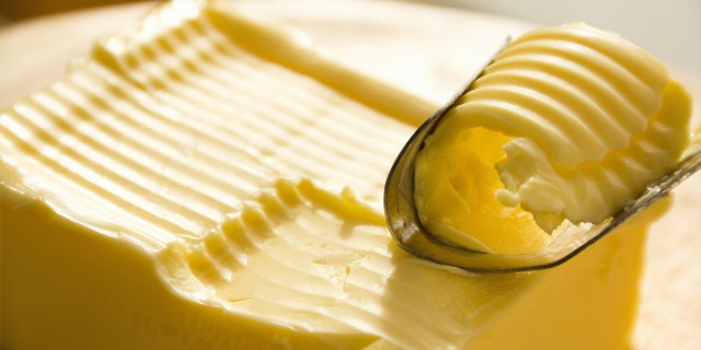 A butter knife with visible holes is used to slice butter.