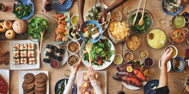 People eat at a table filled with food.