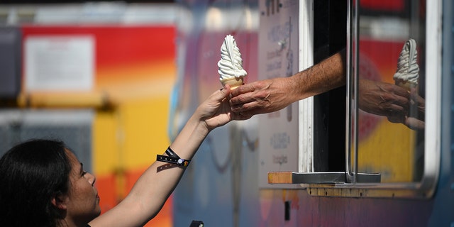 A woman being handed ice cream from an ice cream truck
