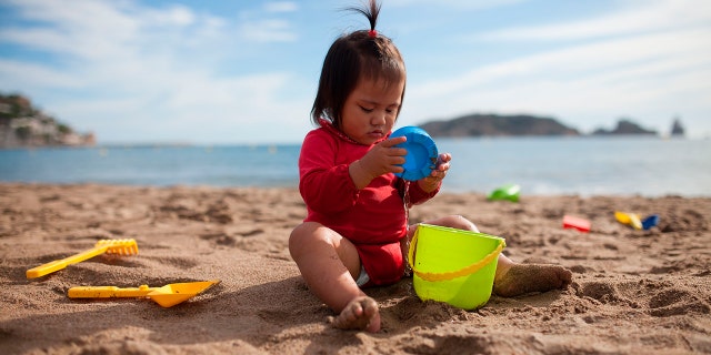 A young child playing in the sand at the beach