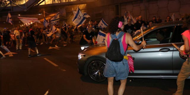 Protestas en Tel Aviv: Miles de israelíes se manifiestan contra la renuncia del jefe de policía; El caos explota 5 Un coche en una protesta israelí