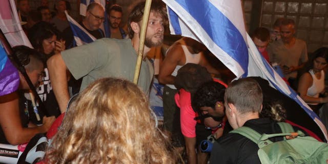 Protestas en Tel Aviv: Miles de israelíes se manifiestan contra la renuncia del jefe de policía; El caos explota 6 Un hombre ondea la bandera israelí