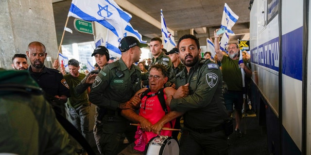 Protestor being escorted from Ben Gurion Airport in Israel