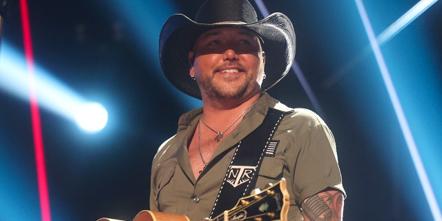 Jason Aldean wears black cowboy hat on stage while performing