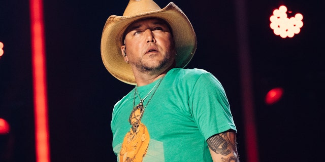 Country singer Jason Aldean performs on stage in cowboy hat and green shirt