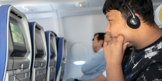 A young boy watching a movie on a plane