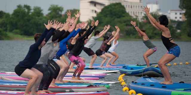 Group of people participating in paddleboard yoga