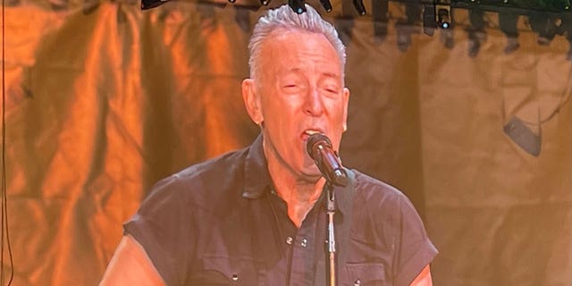 Bruce Springsteen canta en el micrófono mientras actúa en el escenario