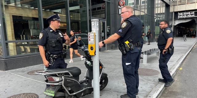 NYPD officers standing near scooter