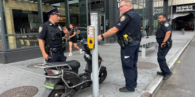 NYPD officers standing near scooter