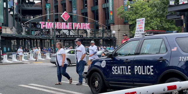 Baseball fans cross in front of Seattle police car