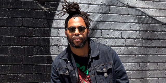Seneca Scott sits in front of a mural in his neighborhood