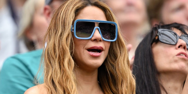 Shakira with large black sunglasses with blue trim around them at Wimbledon