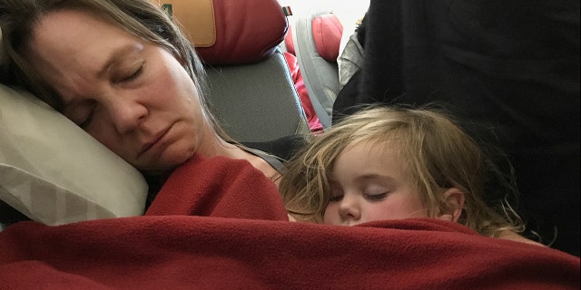 A mother and daughter asleep on a plane